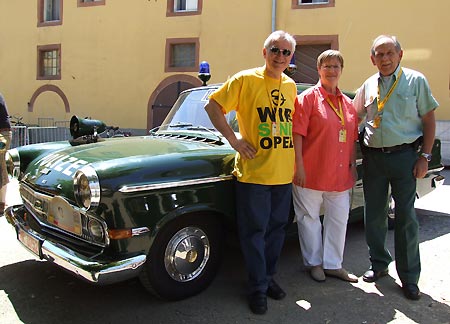 Opel-Chef Hans Demant, der mit seiner Ehefrau Angelika und Hans-Heinrich Menche vor dem Polizei-Opel Kapitn