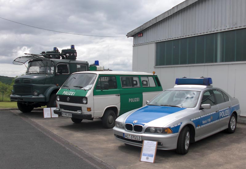 v.l. Polizei-Wasserwerfer, VW-Bus, Typ T3, und 5er BMW vor einer Museumshalle