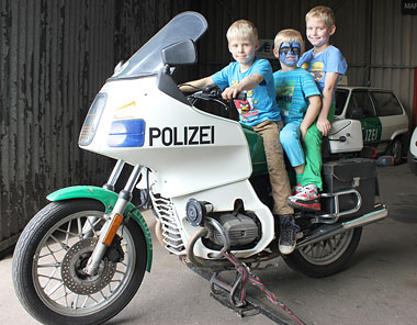 Drei Jungs nutzten die einmalige Chance für ein Bild auf dem Polizeimotorrad der Marke BMW R 65