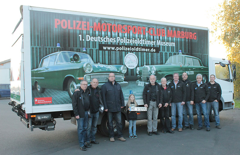 Michael Deuker (links) zusammen mit den PMC-Mitgliedern auf der Hebebühne bei der Übergabe des neuen Lkw vom Typ „Mercedes Atego“ an das 1. Deutsche Polizeioldtimer Museum - und neben dem Fahrzeug - unten